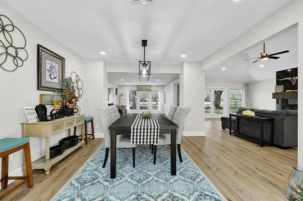 This elegant formal dining room features a stylish modern chandelier, recessed lighting, and an open-concept design that flows seamlessly into the living area. With large windows offering a serene golf course view, this space is perfect for entertaining or intimate gatherings