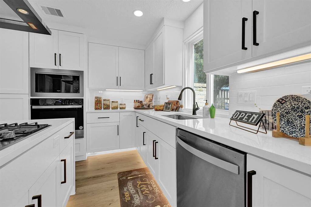 This fully reconfigured and renovated kitchen boasts sleek quartz countertops, custom cabinetry, and modern stainless steel appliances for a high-end culinary experience. Enhanced with under-cabinet and accent lighting, this bright and inviting space perfectly blends functionality and style