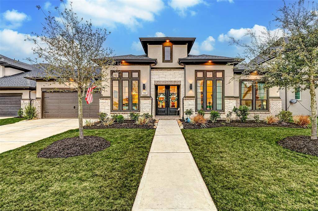 Modern brick and stucco exterior with pristine landscaping and custom soffit light package offers impressive curb appeal in Cross Creek Ranch.