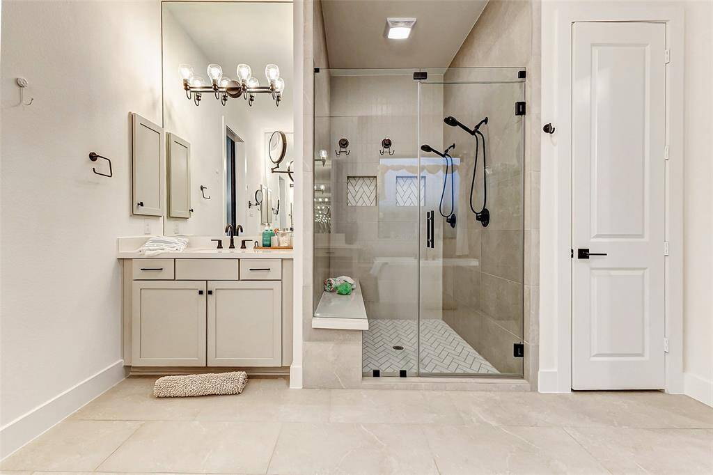 Separate vanities with beautiful dove gray shaker cabinets with modern pulls provide storage and more.