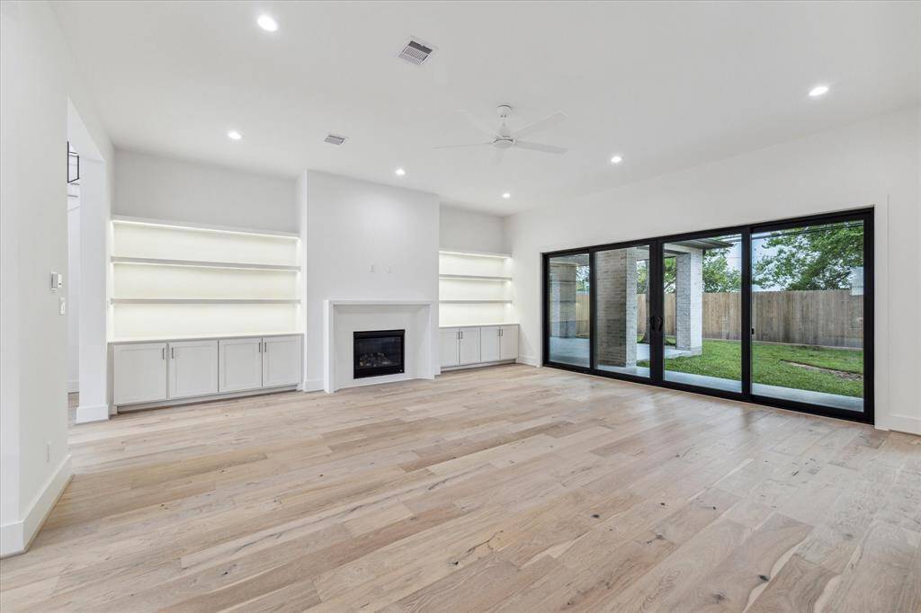 Family Room - Built-in storage and display shelves featuring Phantom Lighting, wall of glass overlooking pool size yard and covered access to Summer Kitchen / Lanai.
