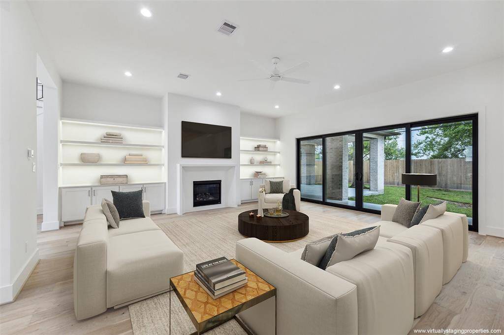 Virtually staged family room with view toward backyard and lanai. Great storage / display with phantom under-shelf lighting and cast stone fireplace.