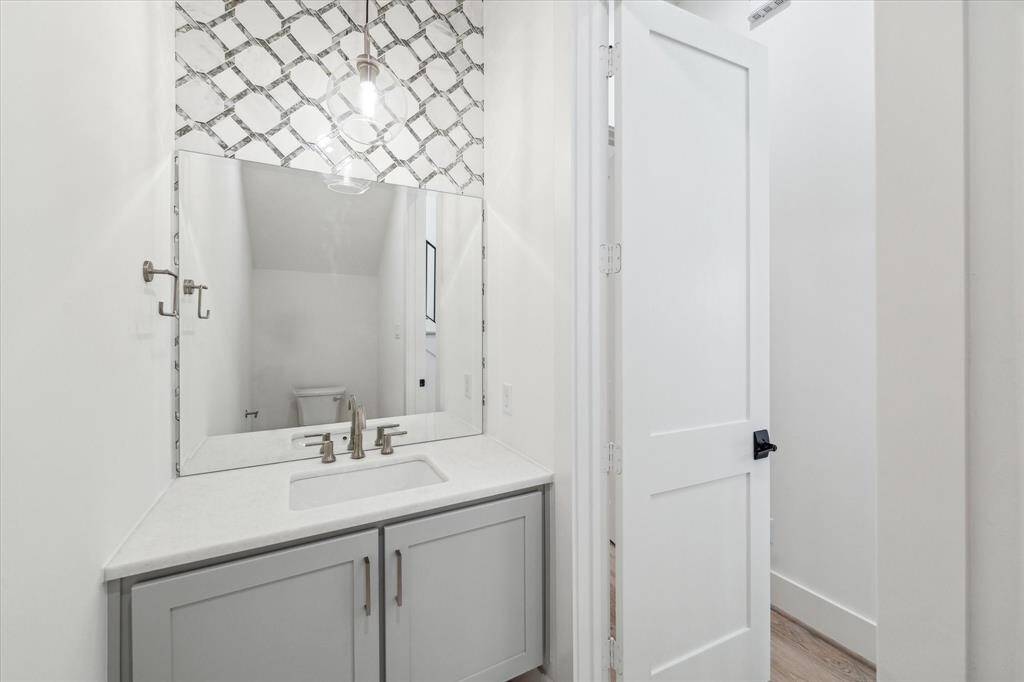 First floor powder bath features Carrara Marble countertop, ceramic tile floor and Carrara Marble backsplash mosaic.