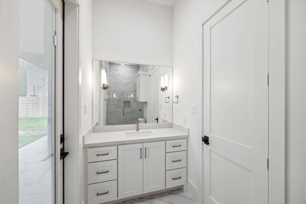 Downstairs bedroom with en suite bath features quartz countertop vanity, ceiling ceramic tiled shower and conveniently opens to lanai.