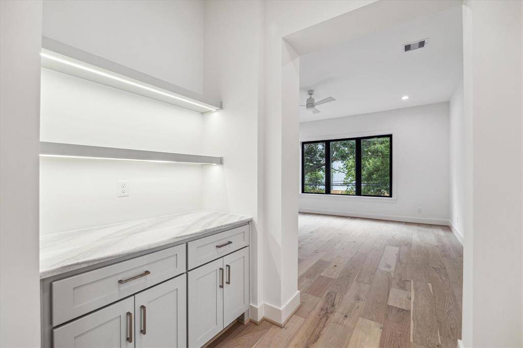Primary suite vestibule entry features display shelving with Phantom Lighting, quartz counter top and additional undercounter storage.