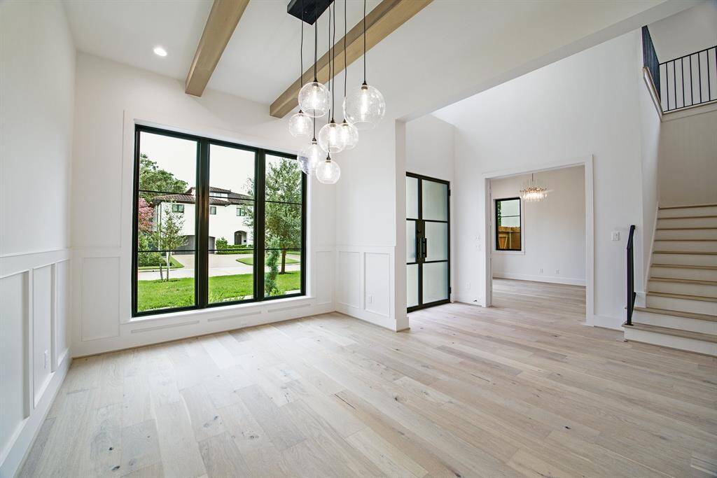 View of formal dining room with beamed ceiling & wainscotting through to foyer and on to study / formal living room in background.