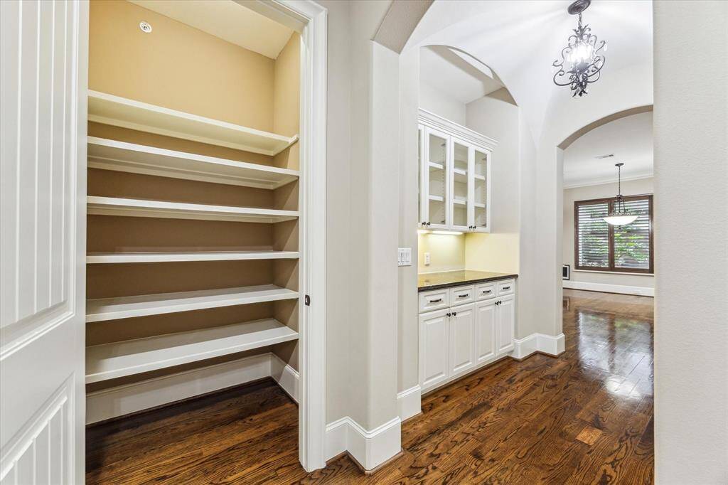Located off the foyer are the elevator closet and dry bar, offering convenient storage and serving space. Arched opening leads to the open-concept living areas.