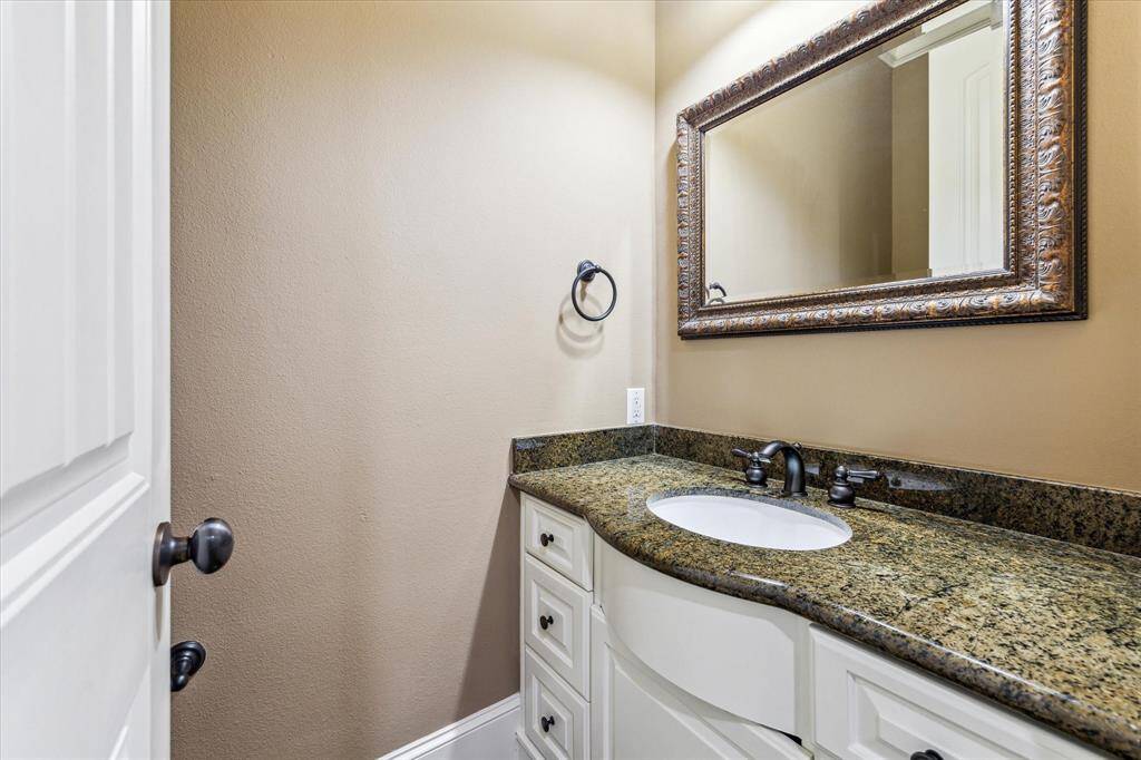 Half bath is located off the foyer and highlights a granite vanity with cabinet/drawer storage below.