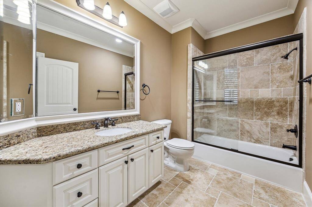 Full bath (adjoins the third bedroom) features a granite vanity with cabinet storage below and a tub/shower combo with sliding glass door.