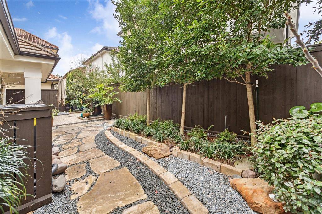 Thoughtfully designed, the private backyard is fully fenced (2024) and features a serene flagstone pathway with a crushed granite inlay, bordered by lush greenery and meticulously maintained landscaping.