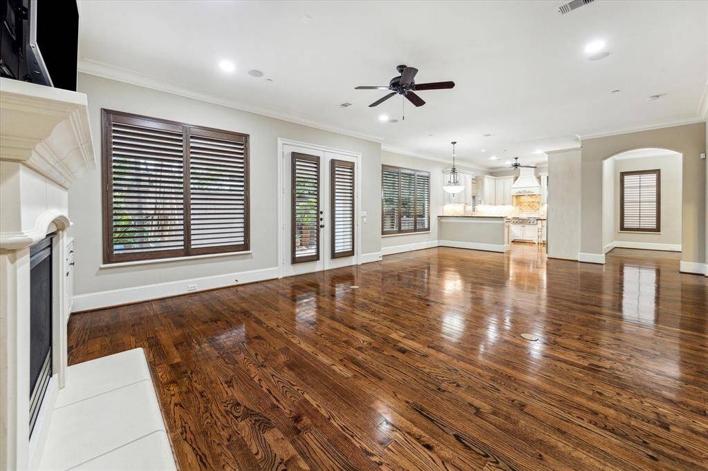 This open-concept living space and hardwood floors seamlessly connects the family room, breakfast room, and kitchen, offering both functionality and flow. Large windows with plantation shutters, and a gas log fireplace enhance the inviting atmosphere, while a convenient access door leads to the backyard. Arched opening leads to the formal dining room.