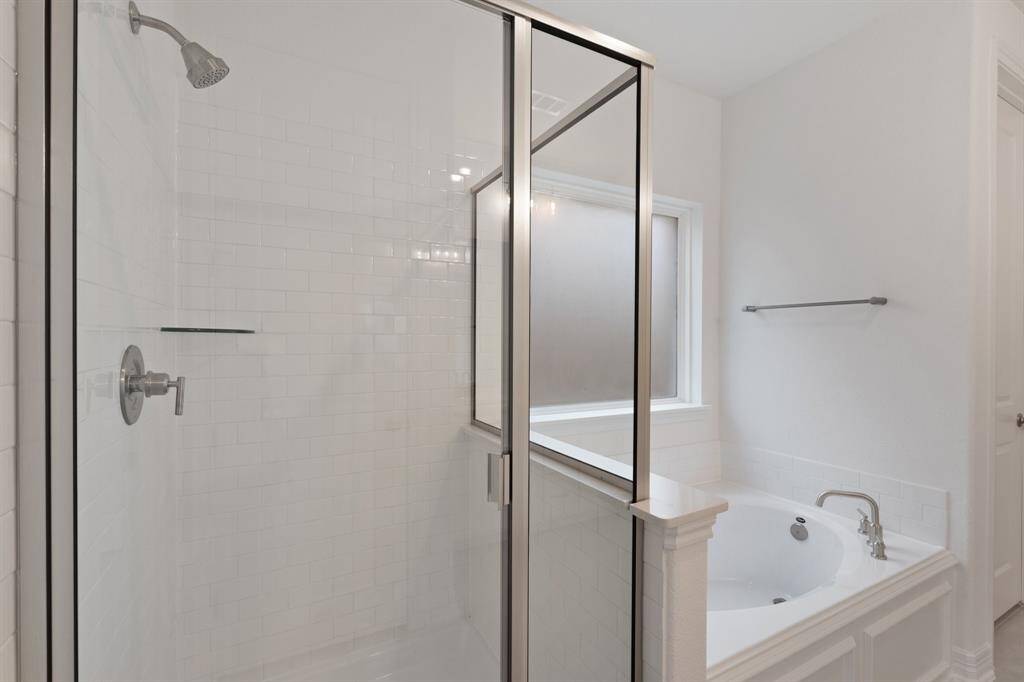 This additional view of your primary bathroom features tile flooring, fresh paint, walk-in shower, a separate garden tub, and a large walk-in closet.