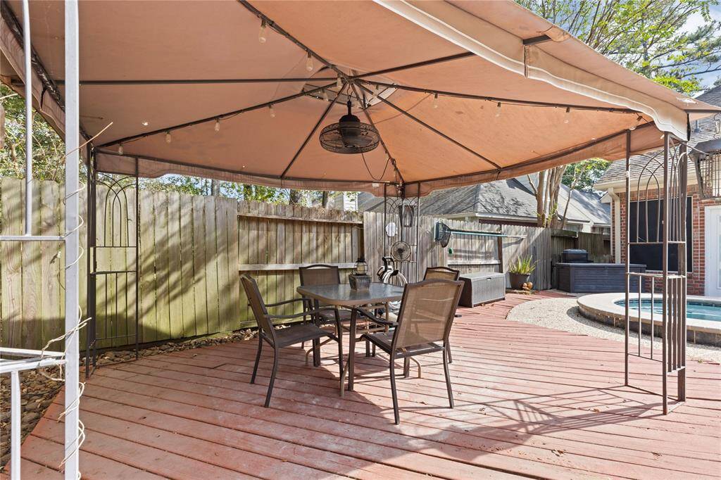 A covered area in the corner of the back yard provides a place to cool around the pool.