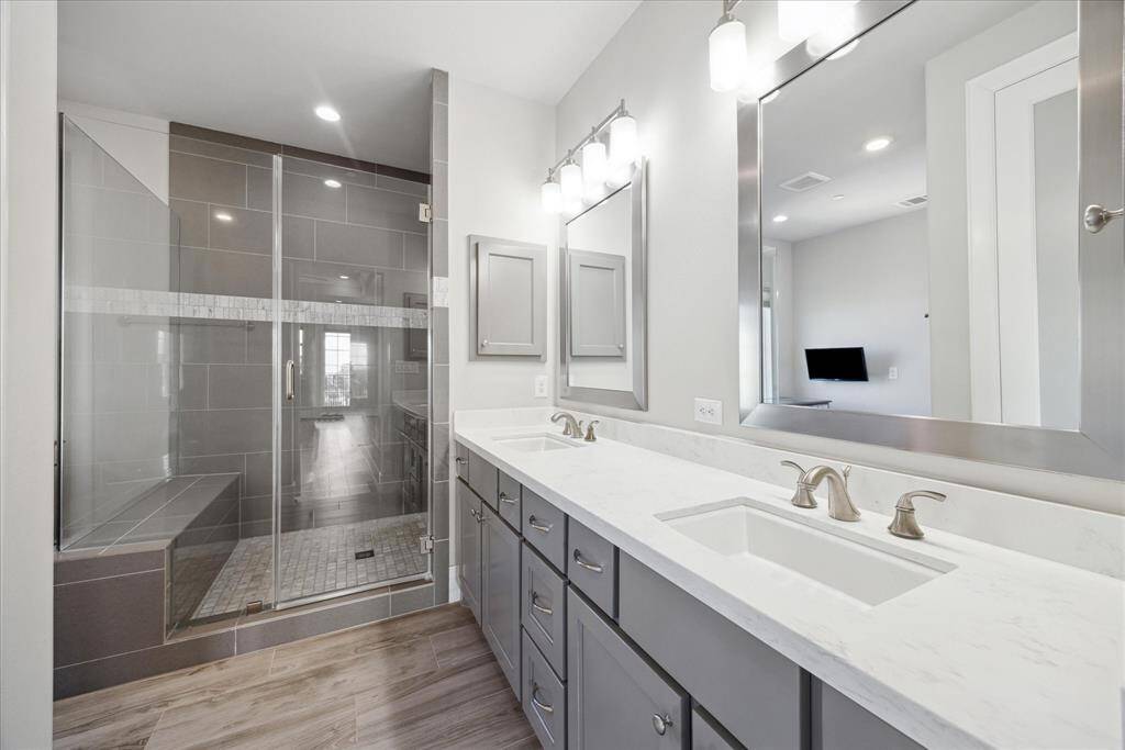 Luxurious primary bath features double sink vanity with plenty of storage, and custom floor to ceiling large tiled shower with bench seating.