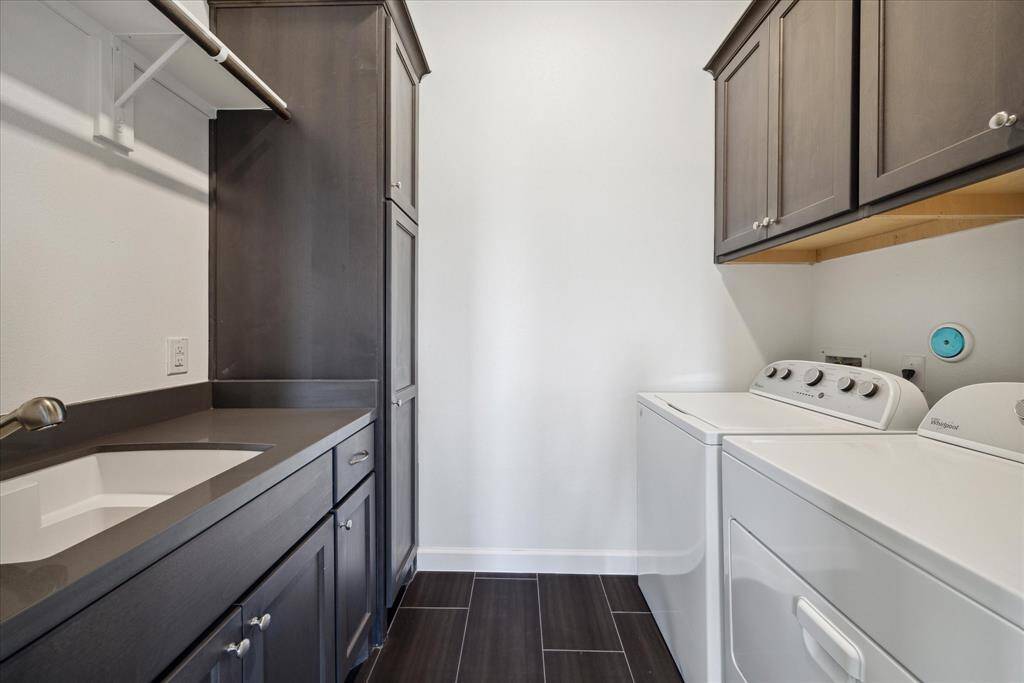 Washer and dryer are included in this third floor laundry room.  Convenient sink, hanging bar and folding space.  Additional storage cabinets.