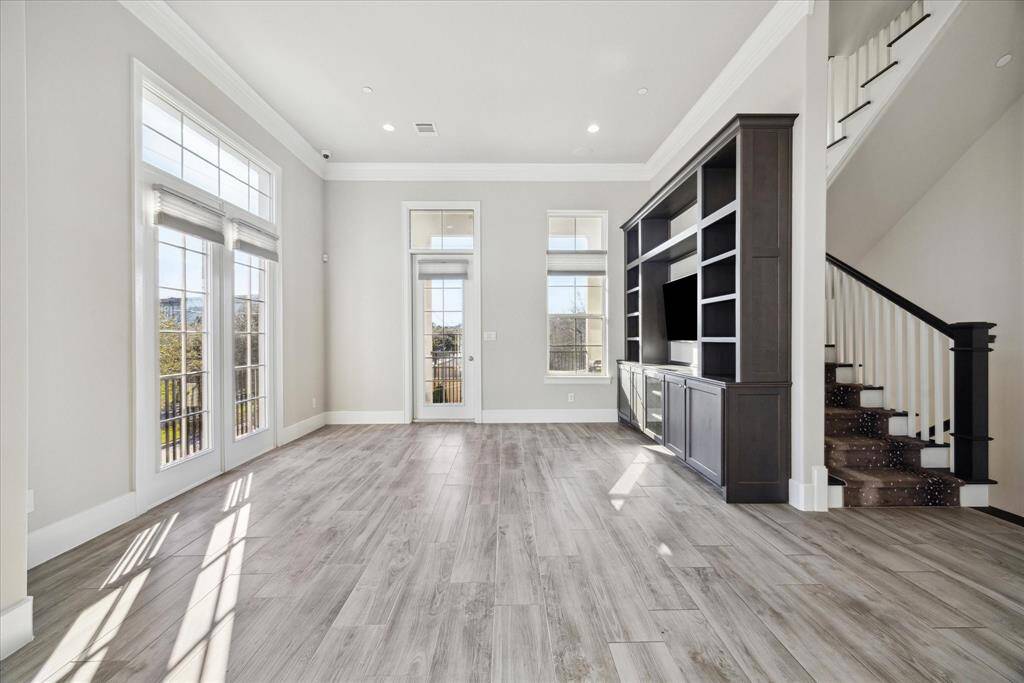 Living room with wall of built-ins and extra walls of windows due to end unit location.  Doorway at end leads to covered balcony with gas line for outdoor grilling and spectacular views.
