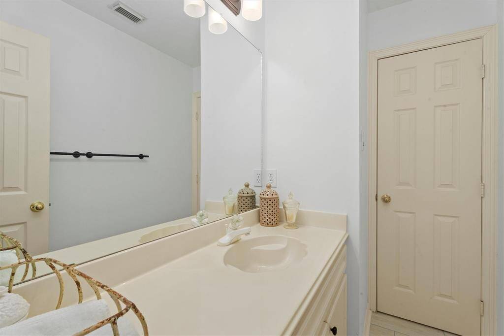 Charming guest vanity with ample lighting and classic finishes that is attached to the secondary bedroom.