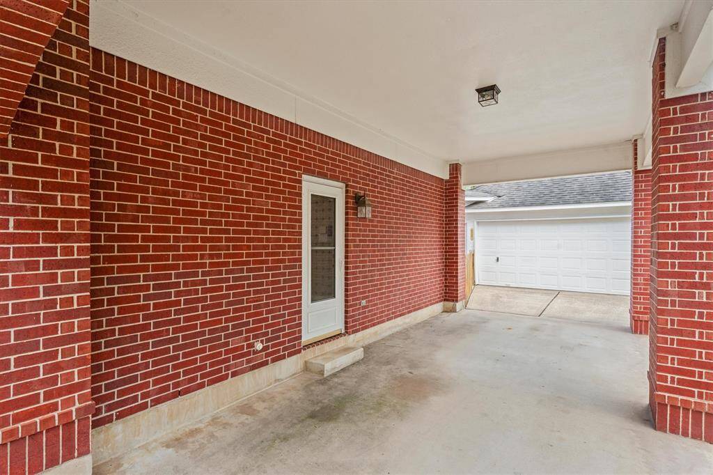 Charming covered porch with convenient access to a spacious garage, set against a beautiful brick exterior.