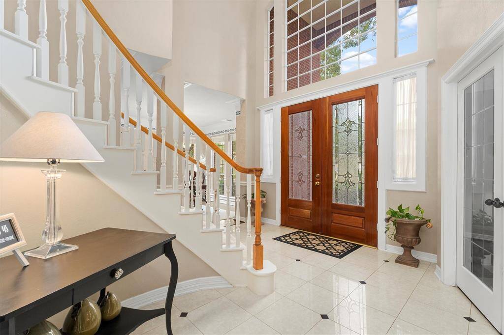Step into elegance with this home's majestic foyer, featuring soaring ceilings, abundant natural light, and stately double doors that lead to a sweeping staircase.
