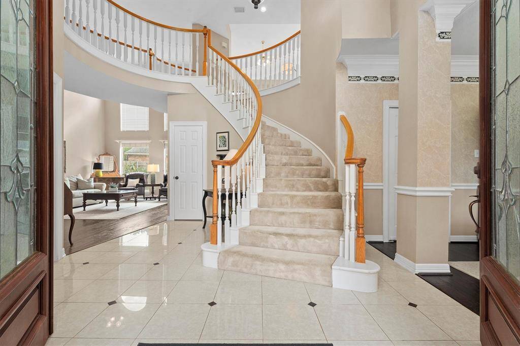 This home's grand entrance, leading directly into a spacious family room perfect for gatherings. To the right lies an elegant formal dining area, while to the left, a private office beckons with its quaint French doors.