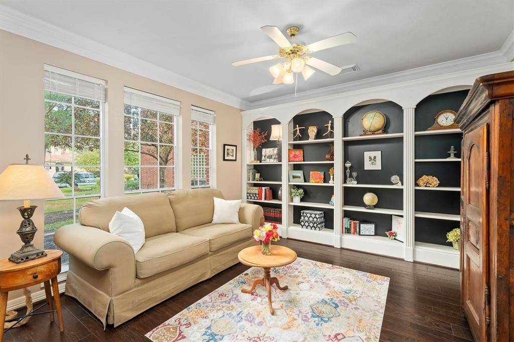 Discover a serene and spacious home office, featuring elegant hardwood floors, custom shelving, and an abundance of natural light.