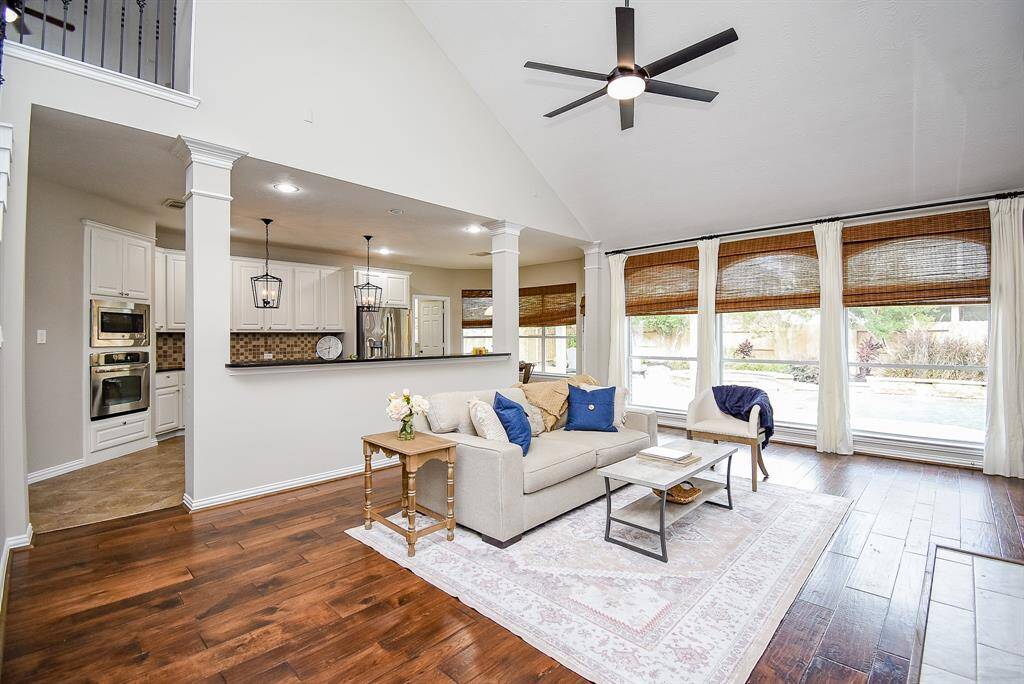 The living room is flooded with natural light from oversized windows, offering picturesque views of the beautiful backyard.