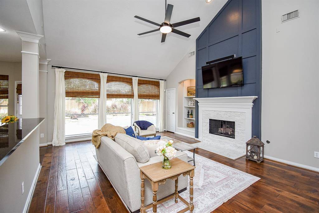 This inviting living room features a stunning floor-to-ceiling accent wall that frames the fireplace and mounted TV, creating a dramatic focal point.
