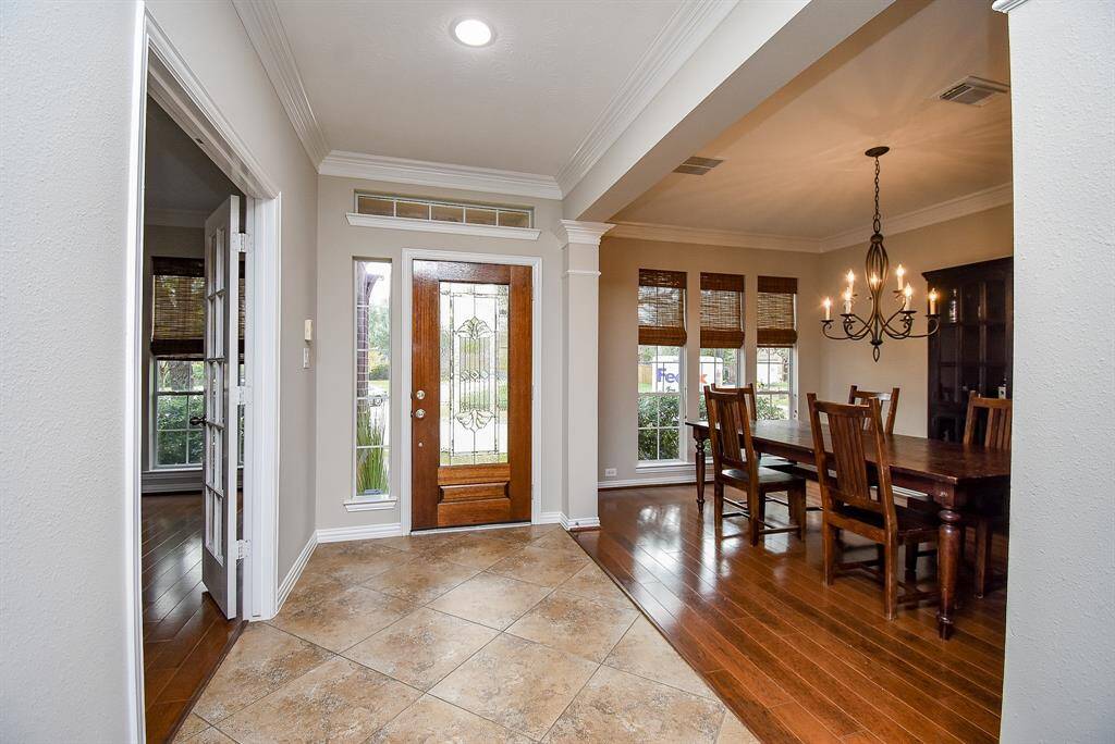 As you step into this stunning home, you are greeted by a beautifully designed entryway featuring tile flooring, a decorative glass front door, and crown molding that adds a touch of sophistication. The natural light streaming in from the sidelights and transom window enhances the welcoming ambiance.