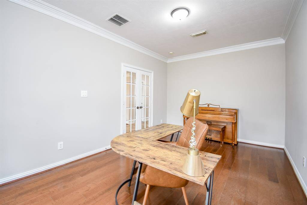 The rich hardwood floors and crown molding enhance the study's design, while the neutral color palette provides a versatile backdrop to suit any decor.