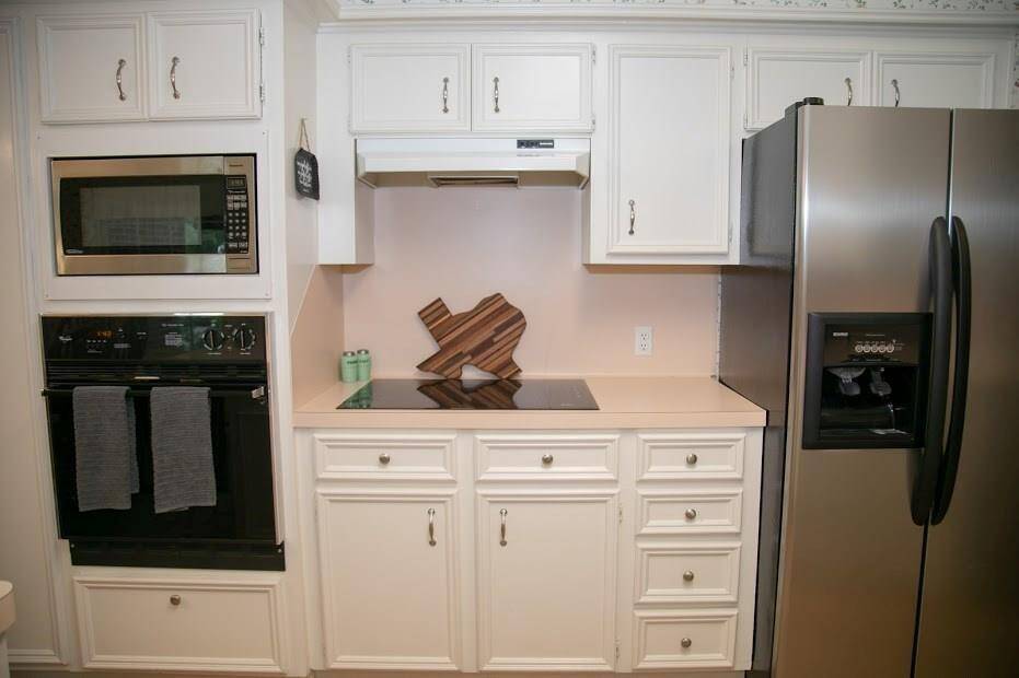 Kitchen showcasing refrigerator, electric cooktop top and microwave.