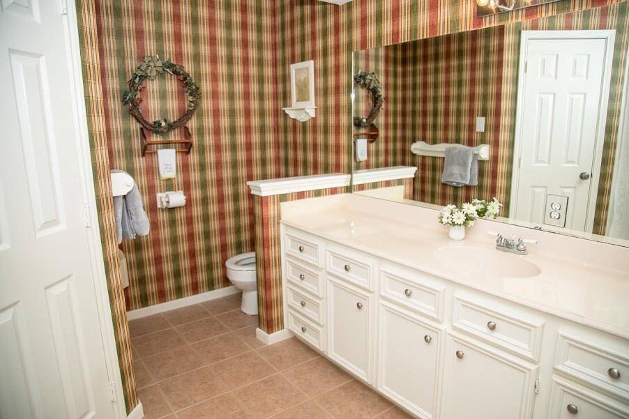 Master bath with wallpaper and tile floors. Lots of cabinet space.