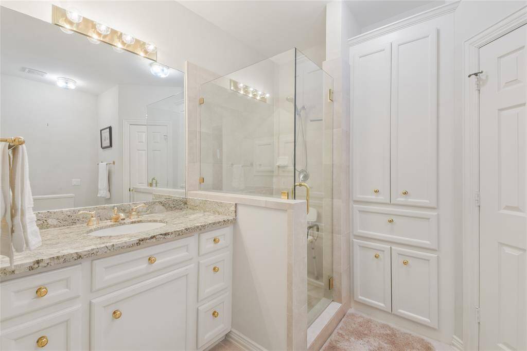 Welcome to his bathroom, a spacious and well-appointed retreat featuring a glass-enclosed shower, elegant granite countertops, and ample storage within white cabinetry. Bright lighting and modern fixtures enhance the clean, sophisticated aesthetic, creating a stylish and functional space. HUGE CLOSET