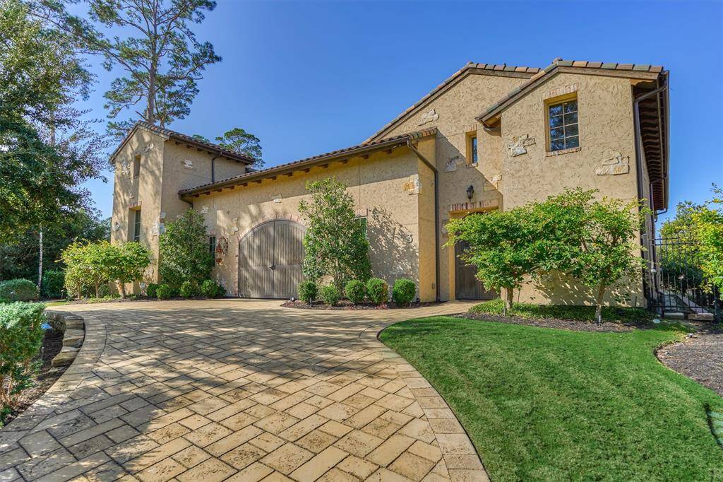 Front of the second home faces Wollaston Court, showcasing a stunning Tuscan-inspired facade with rustic stone accents and arched wooden gates leading from circular driveway to the private motor court.