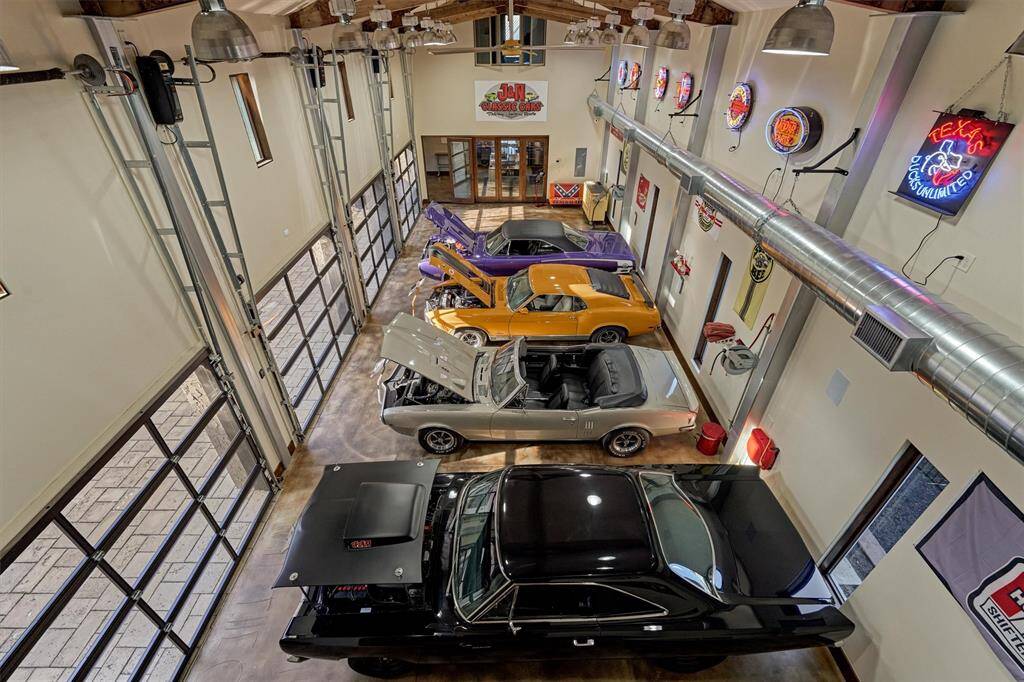 Captured from an elevated vantage point, this image showcases the remaining four bays of the state-of-the-art climate-controlled garage, completing the impressive eight-bay layout. Lined with sleek glass roll-up doors, the space is bathed in natural light.