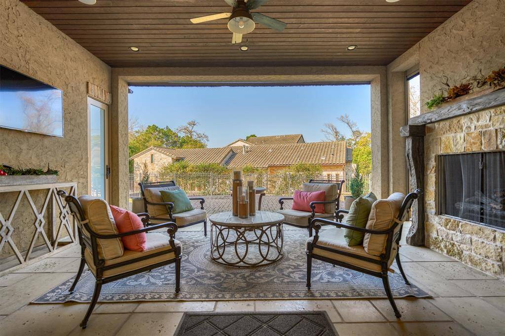 Elegant doors from the dining room open to a spacious covered patio featuring a cozy fireplace, offering a picturesque view of the back exterior of the main home.