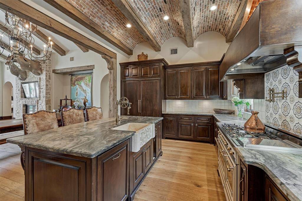 Leathered granite countertops enhance the luxurious tone, while Chicago brick barrel ceiling and exposed wood beams add to the authenticity of the Italian-inspired design.