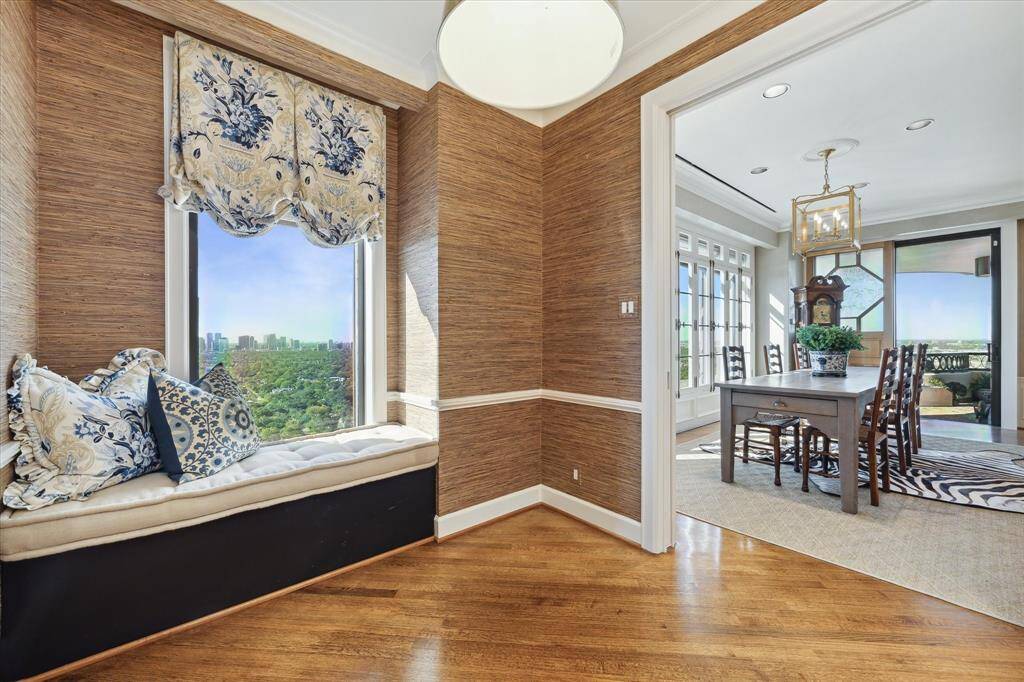 Enjoy morning coffee or casual meals in the breakfast room featuring designer window coverings, Schumacher grass cloth wallpaper, and a built-in window seat with storage.