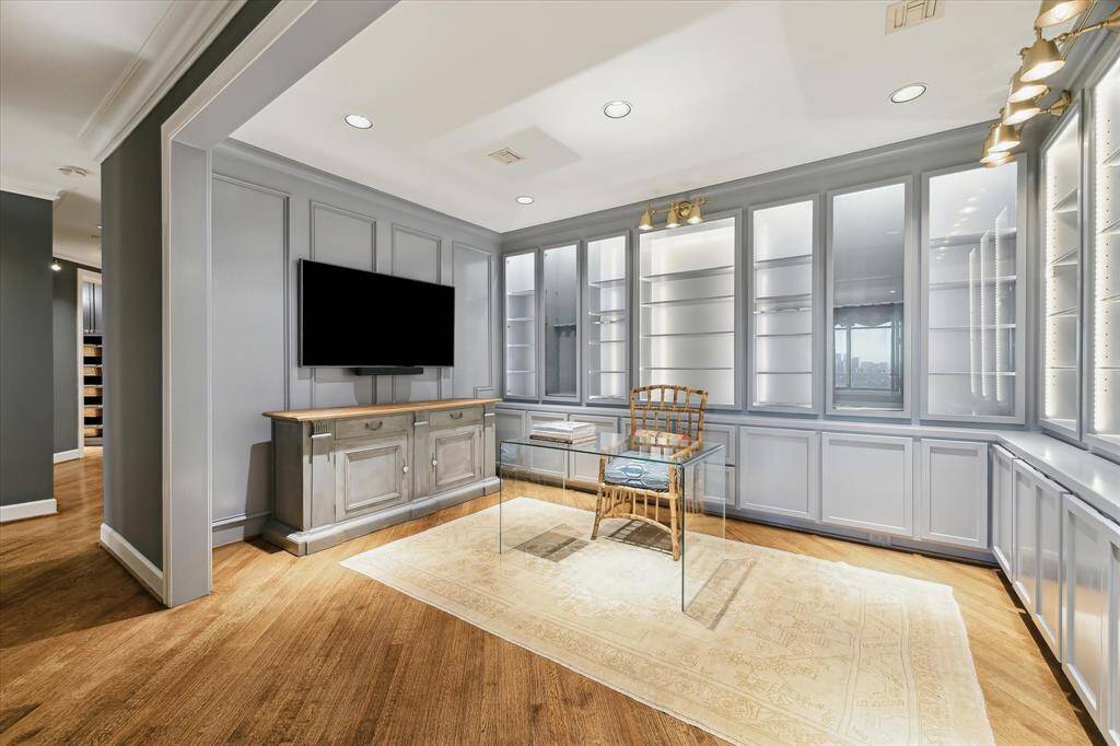The sophisticated library is ideal for working from home or peaceful contemplation thanks to custom built-in cabinetry featuring LED backlighting and brass library lighting by Visual Comfort.