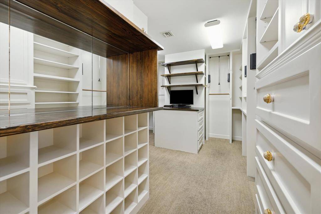 The primary suite’s expansive custom walk-in closet organizes even the largest wardrobes with built-in shelving, drawers, and pull-down rods.