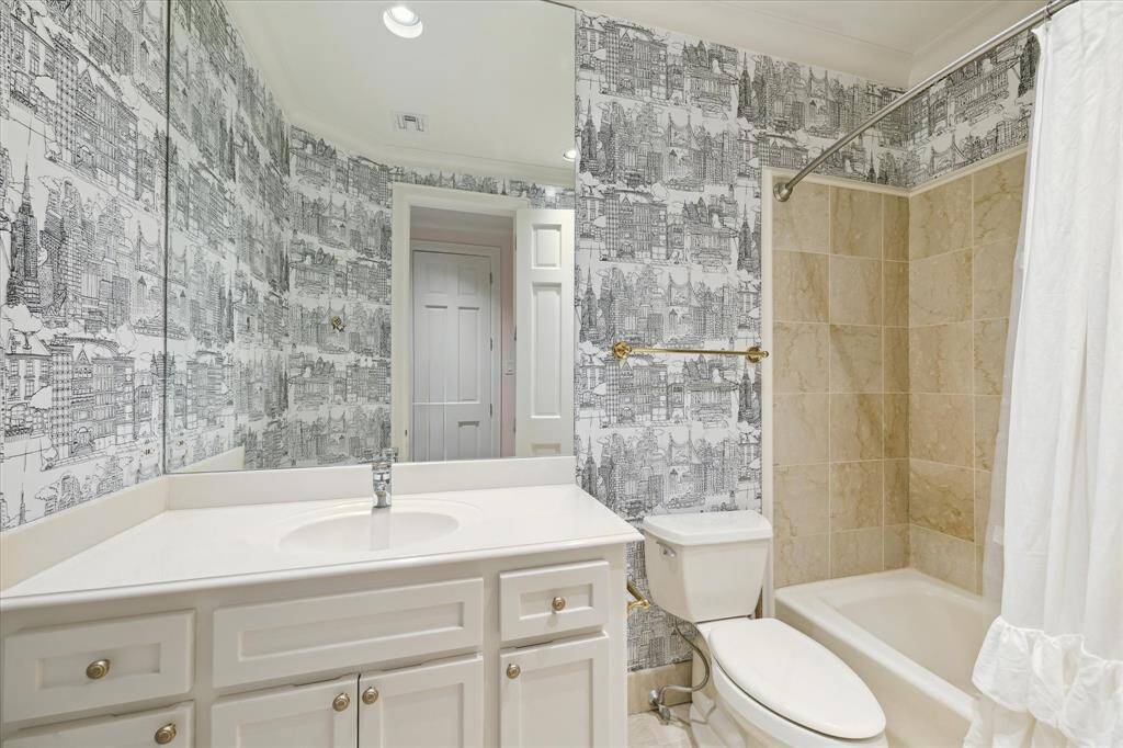 This en suite secondary bathroom boasts a large tub shower and built-in vanity surrounded by Schumacher’s New York New York wallpaper.