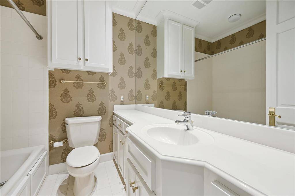This en suite secondary bathroom is filled with an extra-wide vanity, tub/shower and headknocker cabinet for generous storage.