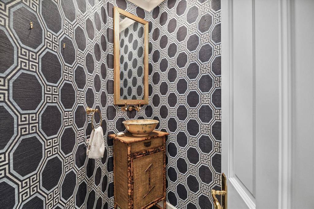 In the stylish powder room, a custom sink and vanity are joined by timeless Schumacher wallpaper adorned with Greek keys and hexagons.