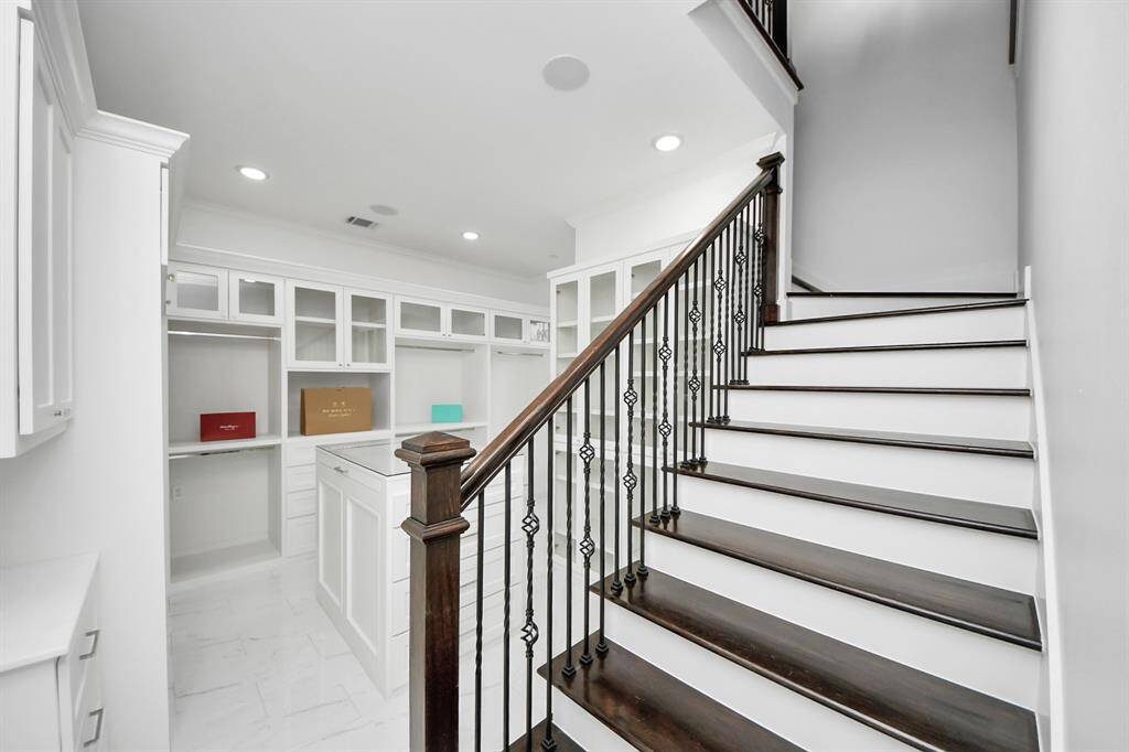 Here we see the beautiful stairway leading to the upper level of this amazing primary suite closet...