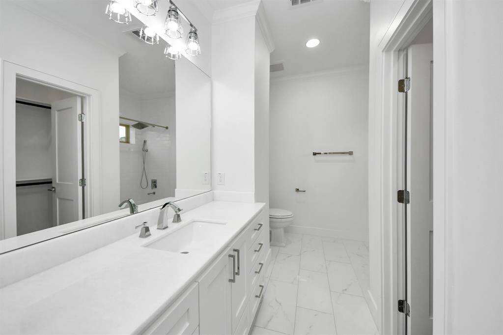 The spacious ensuite bathroom is elegantly appointed with quartz countertops, marble flooring and designer lighting, and the door to the right leads to the walk-in closet!
