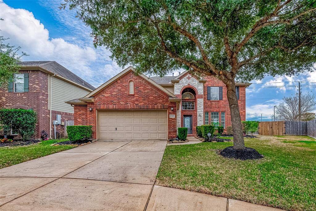 This inviting two-story brick home features a spacious driveway, a two-car garage, and a well-maintained front yard with mature trees. Its charming exterior is a mix of brick and stone accents, offering a welcoming and attractive curb appeal.