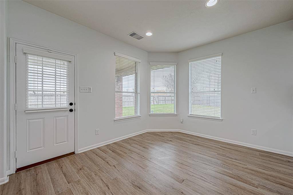 Bright breakfast area with large windows and wood flooring, offering access to the backyard through a side door. Perfect for a cozy sitting area or breakfast nook.