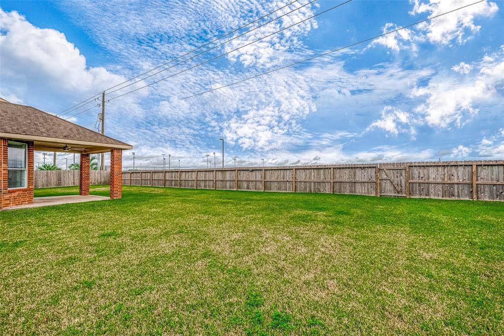 Spacious backyard with well-maintained lawn, privacy fence, and a covered patio area perfect for outdoor activities.