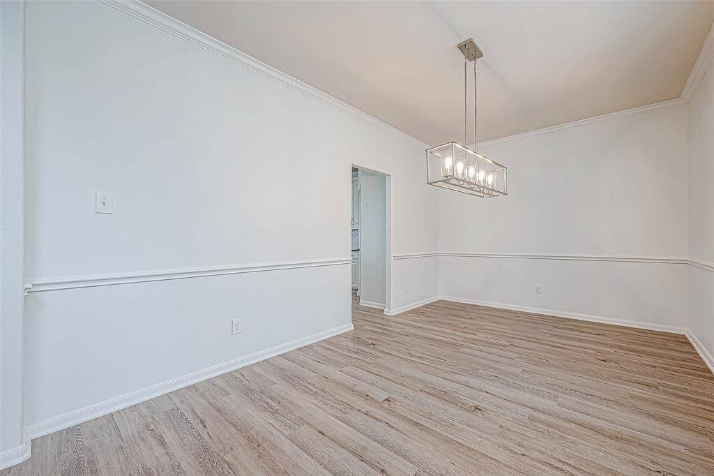 Bright dining area with elegant wood flooring, modern chandelier, and crisp white walls, offering a spacious and inviting atmosphere.