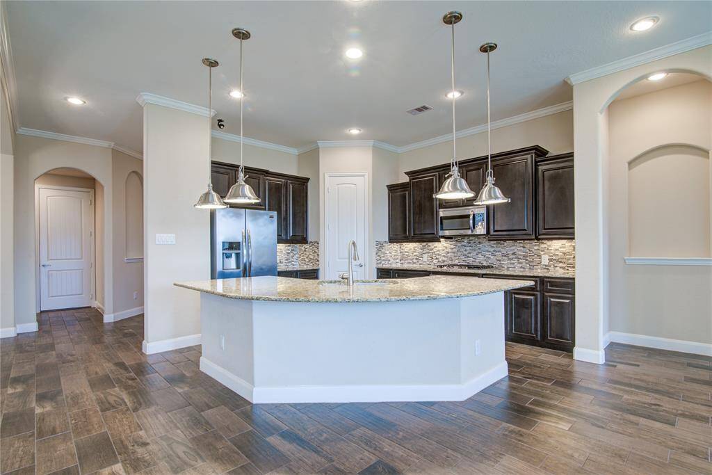 The gorgeous kitchen features a large curved island with breakfast bar seating around the perimeter. Tall cabinetry and modern fixtures make this kitchen a chef's showcase space!