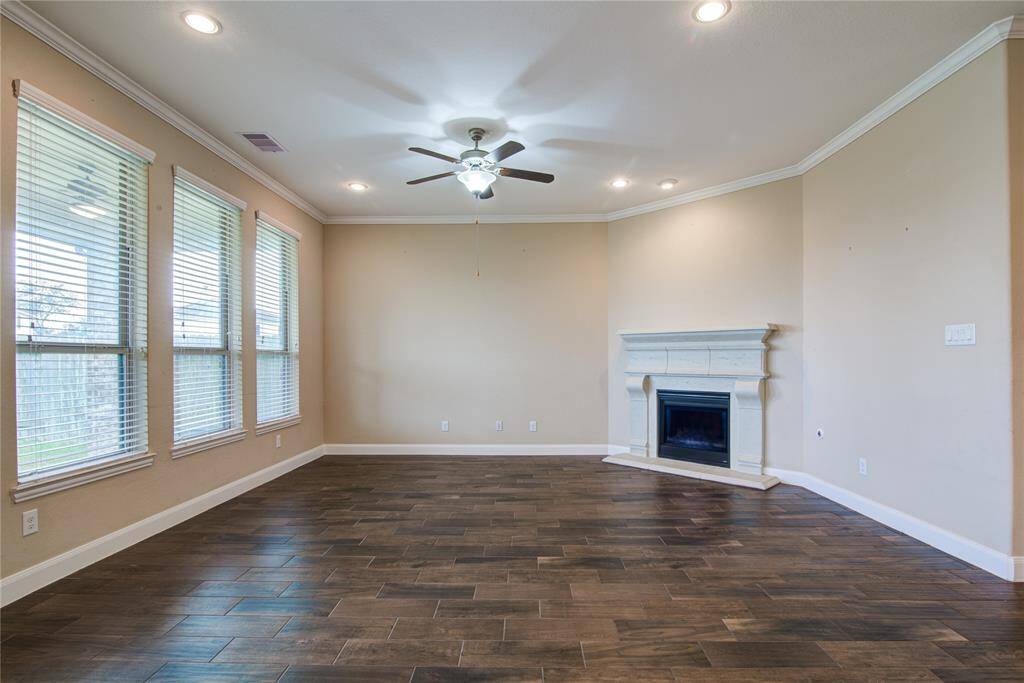 The living room has an abundance of light, with a wall of windows, ceiling fan with light fixture, and additional can lighting.